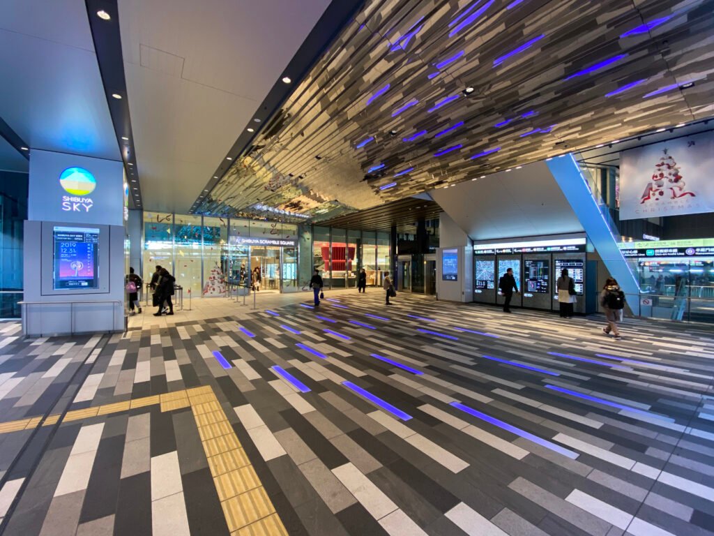 Entrée du bâtiment Shibuya Scramble Square au Japon montrant le logo du Shibuya Sky et l'accès aux ascenseurs de l'observatoire.