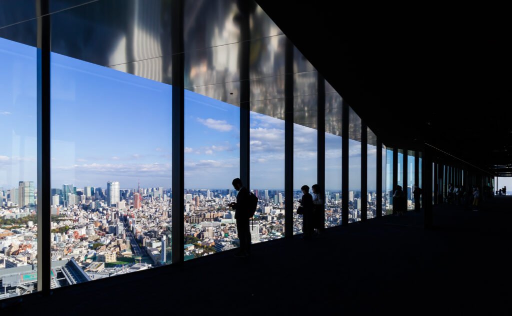 Visiteurs photographiant Tokyo depuis les baies vitrées du Sky Gallery au Shibuya Sky